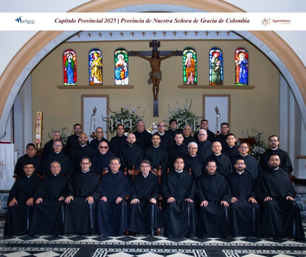 Foto grupal del Consejo Provincial de la Provincia de Nuestra Señora de Gracia de la Orden de San Agustín en Colombia, tomada en el interior de una iglesia con un crucifijo y vitrales al fondo.